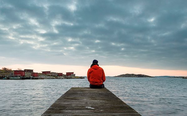 Person sitter vid vatten och sörjer.